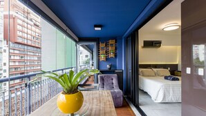 Habitación de hotel moderna con balcón, cama, zona de estar y vista a la ciudad.