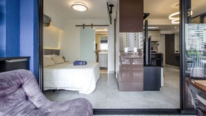 Habitación de hotel moderna con cama, escritorio y vista a la ciudad.