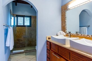 Een badkamer met een douche, twee wastafels en een grote spiegel.
