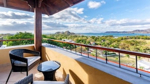 A balcony with wicker furniture and a view of a coastal landscape. - Chic Cliffside Condo w/ Two Balconies Offering Spectacular Ocean & Mountain Views (Playa Flamingo)