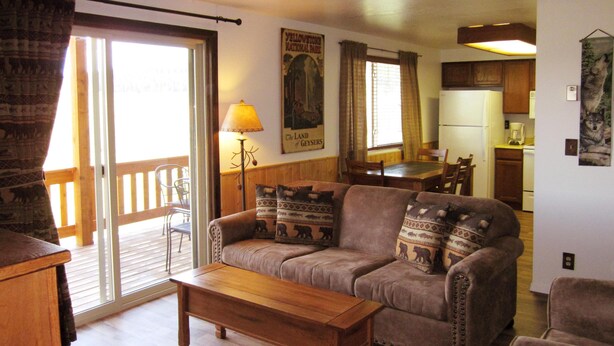 A cozy living room with a sofa, a wooden coffee table, and a dining area with a table and chairs. - Morning Glory-comfortable Yellowstone retreat; just minutes from YNP West Gate (West Yellowstone)