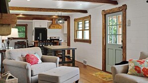 A spacious living room with a fireplace, a dining area, and a kitchen in the background. - Farmhouse just minutes from Hanging Rock, sister property next door ID#3934130 (King)