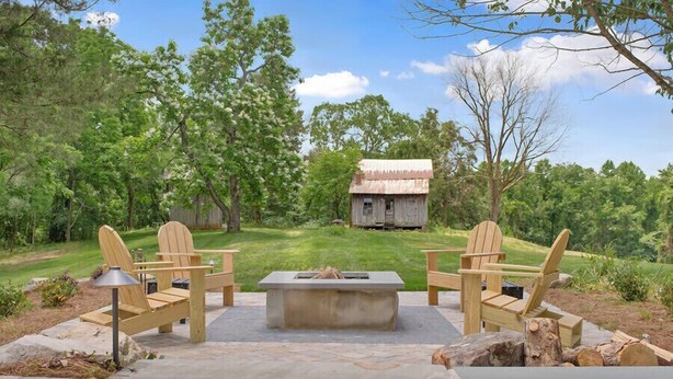 An outdoor patio with Adirondack chairs, a fire pit, and a view of a rustic cabin in the distance. - Farmhouse just minutes from Hanging Rock, sister property next door ID#3934130 (King)