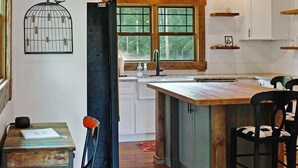 A kitchen with wooden beams, white cabinets, a large island, and a birdcage decoration. - Farmhouse just minutes from Hanging Rock, sister property next door ID#3934130 (King)