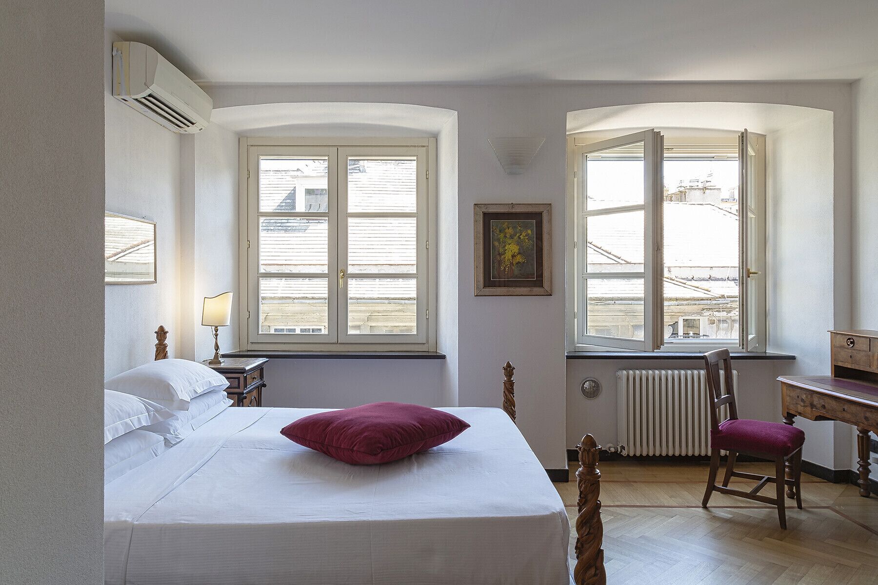 Una camera da letto con un letto, una sedia, una scrivania e due finestre.