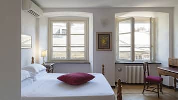 Una camera da letto con un letto, una sedia, una scrivania e due finestre.