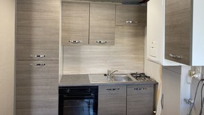 A compact kitchen with a built-in dishwasher, a sink, and a stove. - Furnished duplex studio with air-conditioned parking space (Surgères)