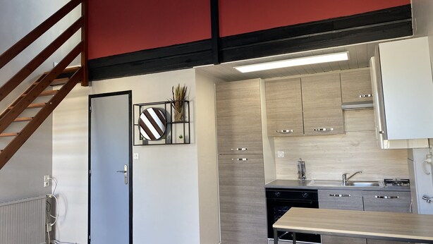 A modern kitchen with a built-in stove, a sink, and wooden cabinets. - Furnished duplex studio with air-conditioned parking space (Surgères)
