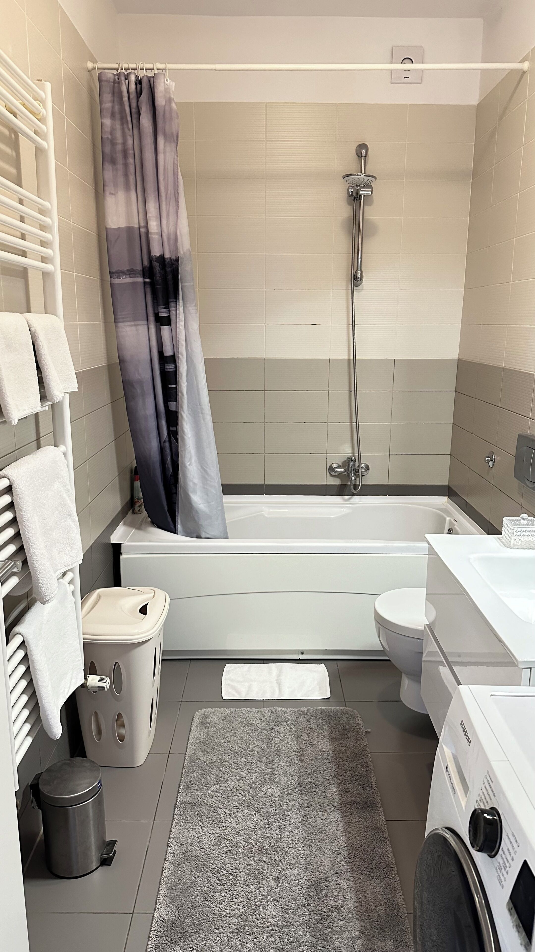 A modern bathroom with a bathtub, shower, toilet, and sink.