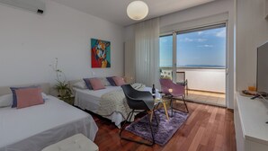 A modern hotel room with two beds, a dining area, and a balcony with a view. - Terra Magica Deluxe Apartment OR Room with Private Parking, Terrace and Sea View (Cavle)