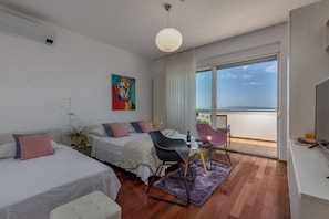 Ett modernt hotellrum med två sängar, en matplats och en balkong med utsikt.
