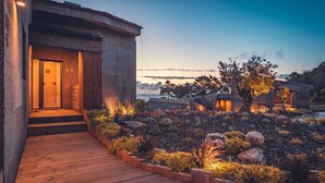 A modern building with a wooden entrance and a landscaped garden with rocks and plants. - Charm Nature (Sintra)