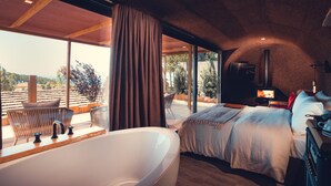 A modern bedroom with a large bathtub, a bed with white bedding, a TV, and a fireplace. - Charm Nature (Sintra)