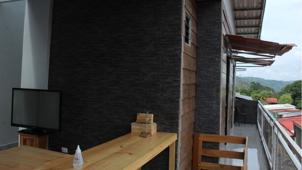 A balcony with a wooden table, a television, and a small plant. - Hotel Pacuare Turrialba (Santa Rosa)