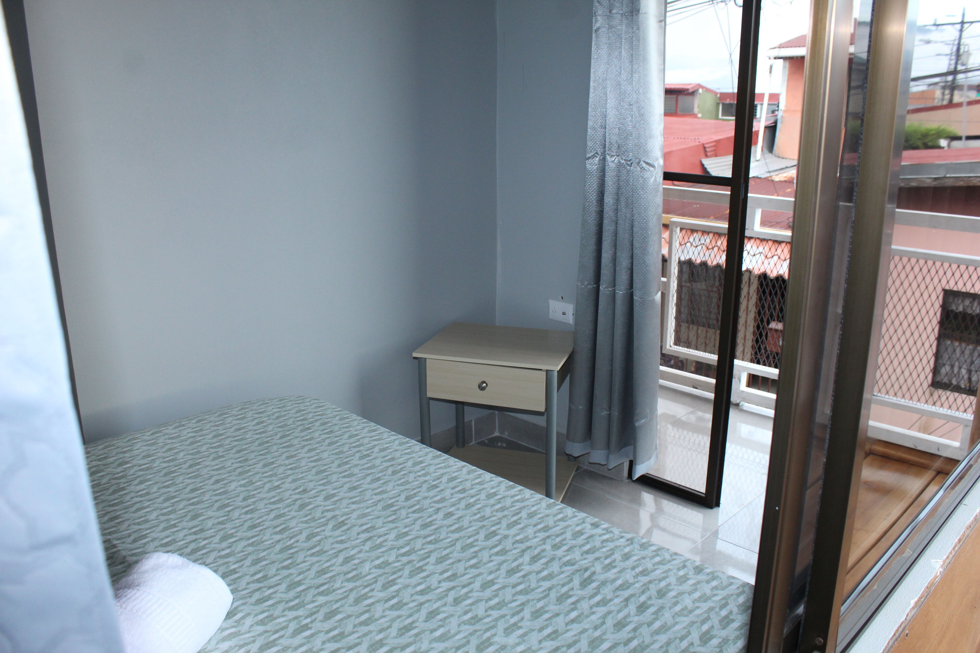 Une chambre à coucher avec un lit, un petit bureau et une fenêtre avec des rideaux.