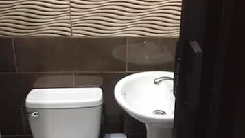 A bathroom with a toilet, sink, and trash bin.