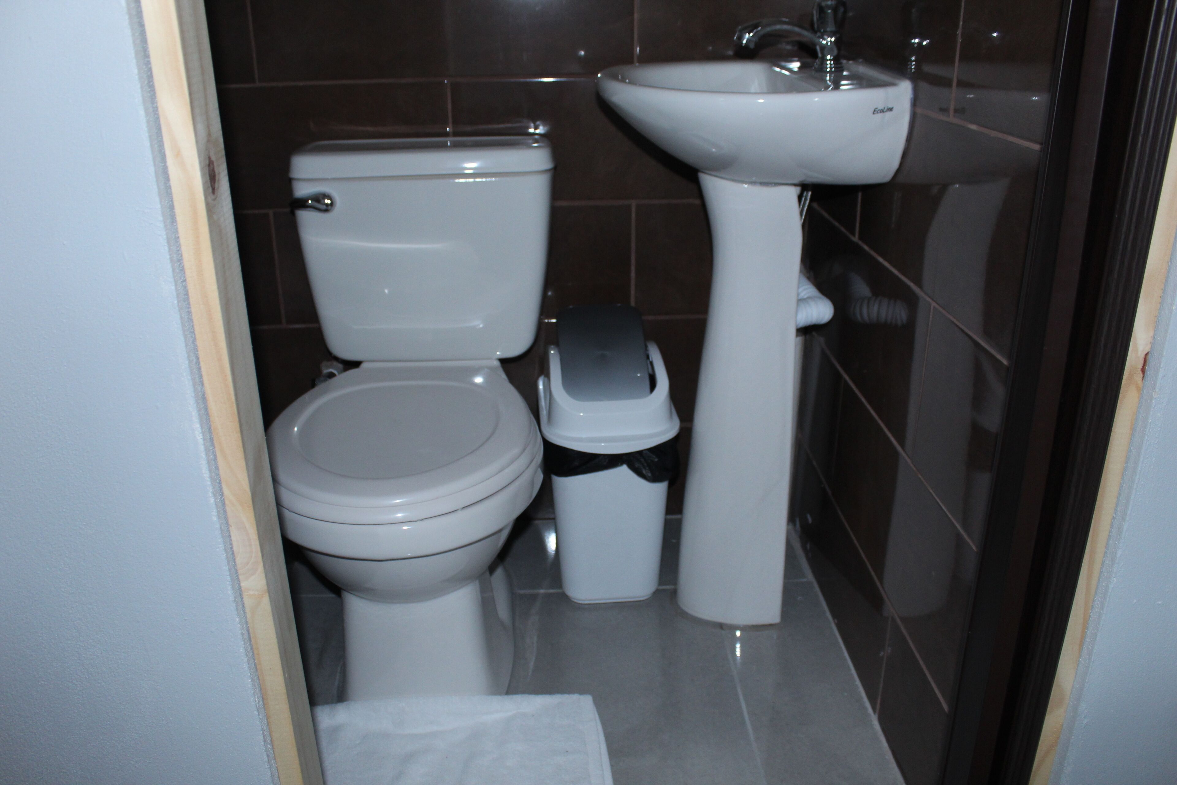 Un bagno con il water, un lavandino e un cestino.