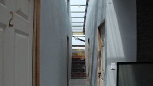 A narrow hallway with a skylight, a wooden door, and a television on the right wall. - Hotel Pacuare Turrialba (Santa Rosa)