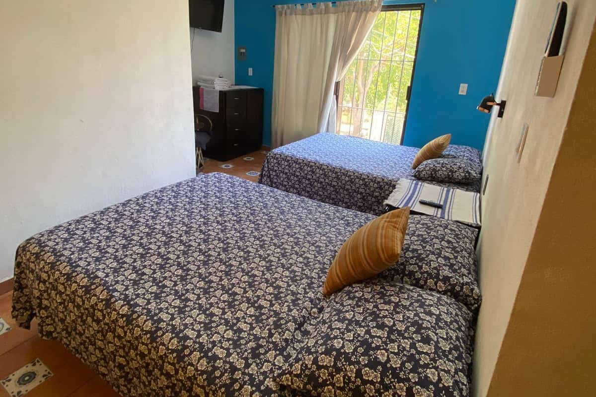 Habitación con dos camas, televisor, ventana con cortinas y aire acondicionado.