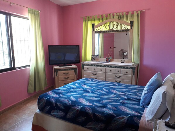 A bedroom with a bed, a dresser, a television, and a mirror. - Familia Sosa Suazo (San José del Cabo)