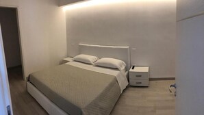 Un dormitorio moderno con cama, mesitas de noche y un velador.