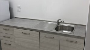 Una cocina moderna con un lavamanos de acero inoxidable, armarios grises y una pared blanca.