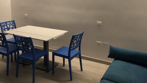 Una habitación con una mesa, sillas, un sofá y una lámpara de pared.