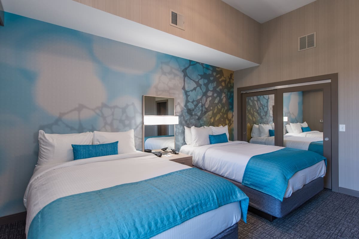 Ein Hotelzimmer mit zwei Betten, einem großen Spiegel und einem Wandbild.