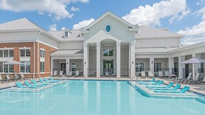 A swimming pool with lounge chairs and a building with a central entrance. - Silver Collection Hotel (Fredericksburg)