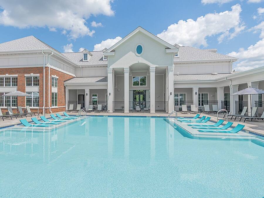 Una piscina con sillas de descanso y un edificio con entrada central.