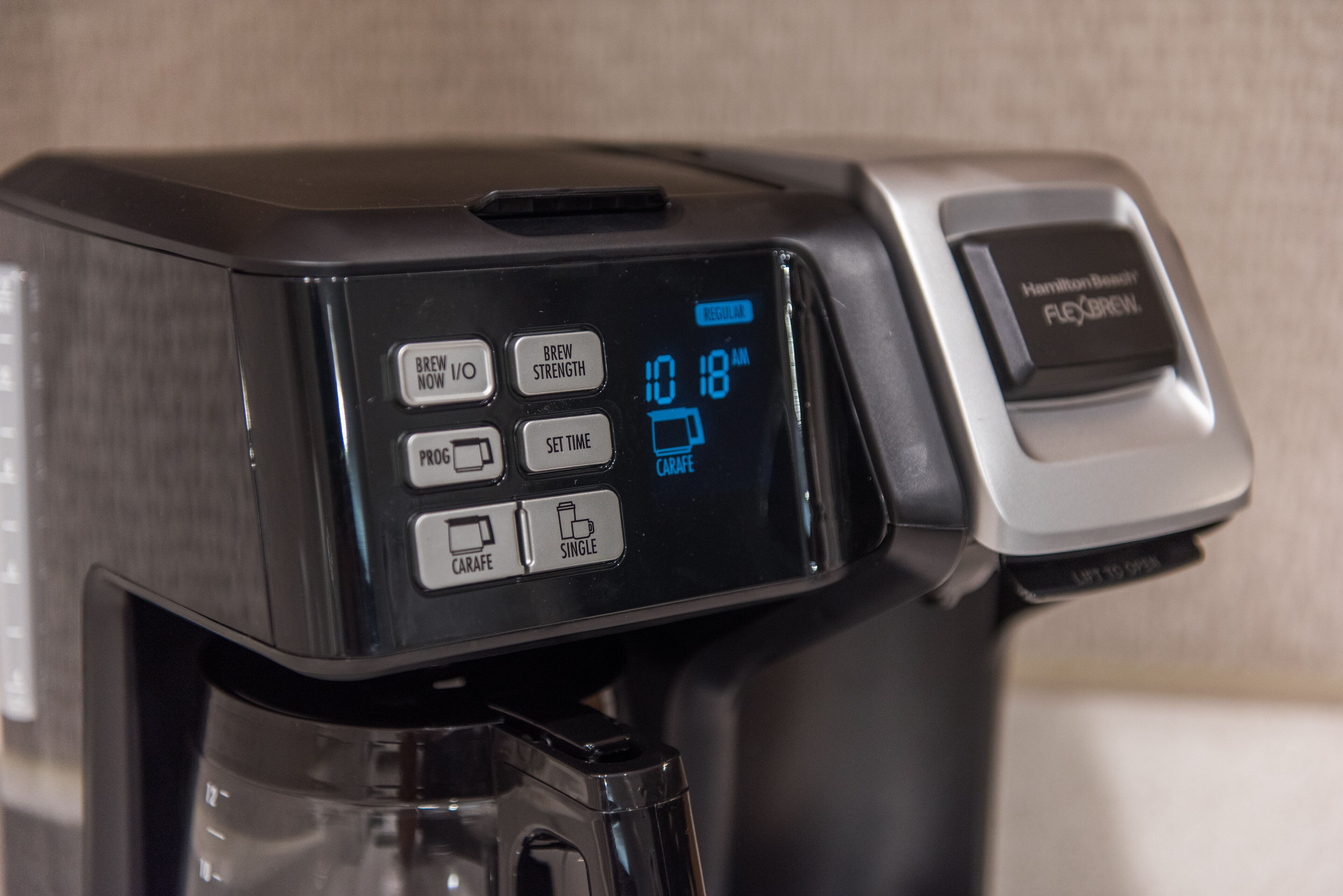 A coffee maker with a digital display showing "10:18 AM" and options like "BREW NOW," "BREW STRENGTH," "PROG," "SET TIME," "CARAFE," and "SINGLE."