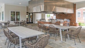 An outdoor patio with a grill station, wicker chairs, and a stone-tiled floor. - Silver Collection Hotel (Fredericksburg)