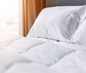 Un lit bien fait, avec du linge de lit blanc et une tête de lit en bois.