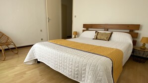A neatly made bed with a quilted white duvet and a mustard-colored throw blanket. - Large T3 loggia in house 500m from the beach (saint cyprien)