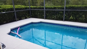 Ein rechteckiger Swimmingpool mit blauer Fliesenverkleidung, umgeben von einer weißen Terrasse.