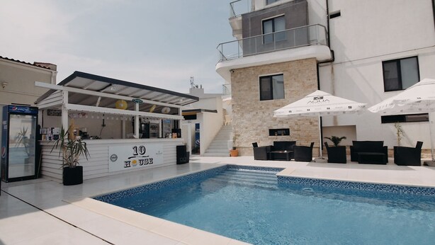 Zona de piscina con bar, asientos al aire libre y una escalera que lleva a un nivel superior.