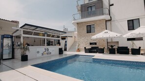 Area piscina con un bar, posti a sedere all'aperto e una scala che conduce a un livello superiore.