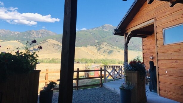 Une cabane en bois dotée d’une véranda donnant sur un paysage montagneux.