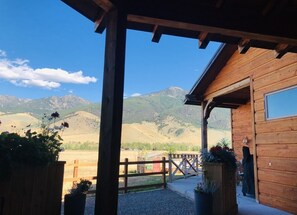 Eine Holzhütte mit Veranda mit Blick auf eine gebirgige Landschaft.
