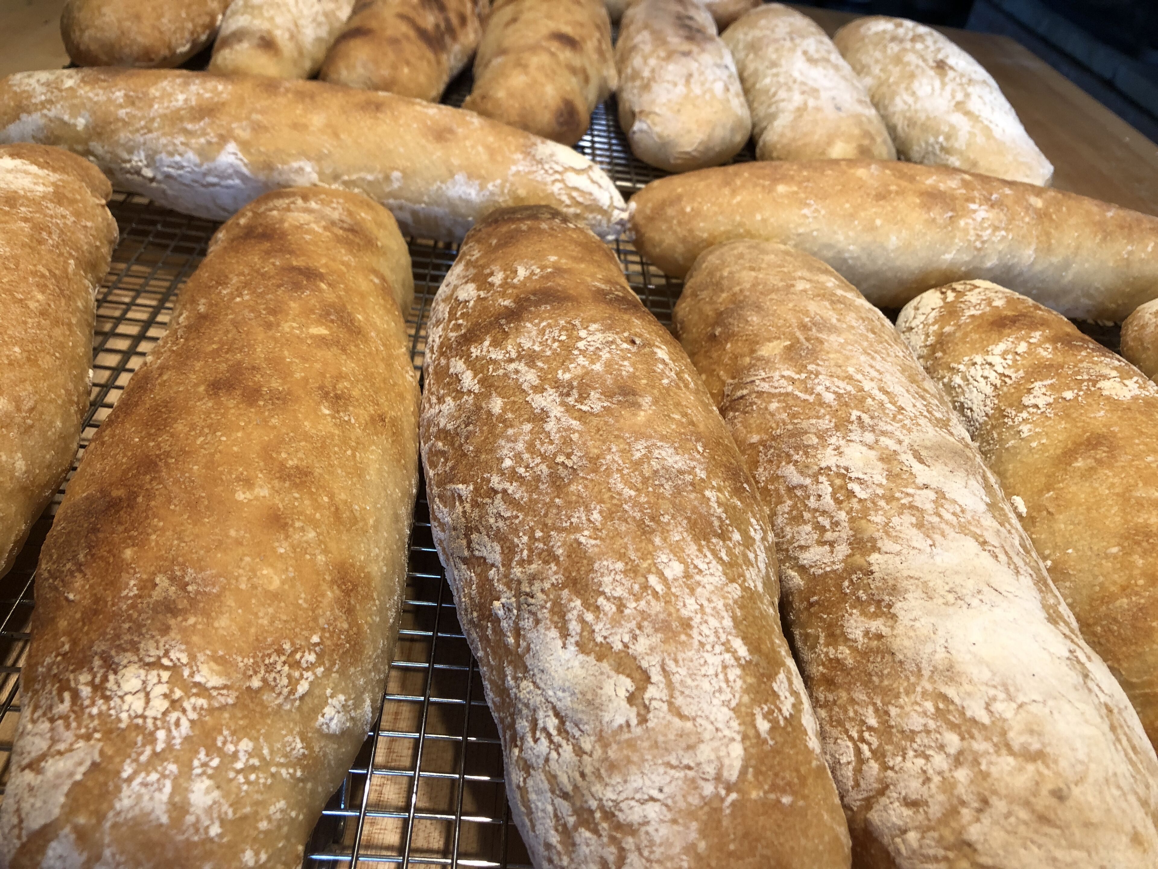 A row of freshly baked loaves of bread on a cooling rack.