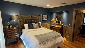 Une chambre à coucher avec un grand lit, une commode en bois, des lampes de chevet et une armoire en bois.