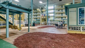 Ein mehrgeschossiges Atrium mit einem zentralen offenen Bereich, einer Schaukel und einer Sitzecke mit Tischen und Stühlen.
