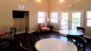 A dining area with tables and chairs, a sign indicating surveillance, and an exit sign.