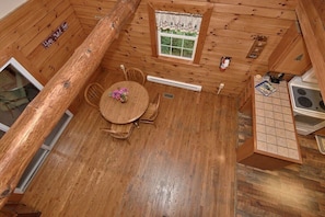 Cozy cabin-style room with a round dining table, small window, and kitchenette area.