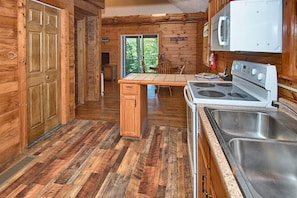 Enjoy cooking in this cabin-style kitchen with a central island, sink, and stove.
