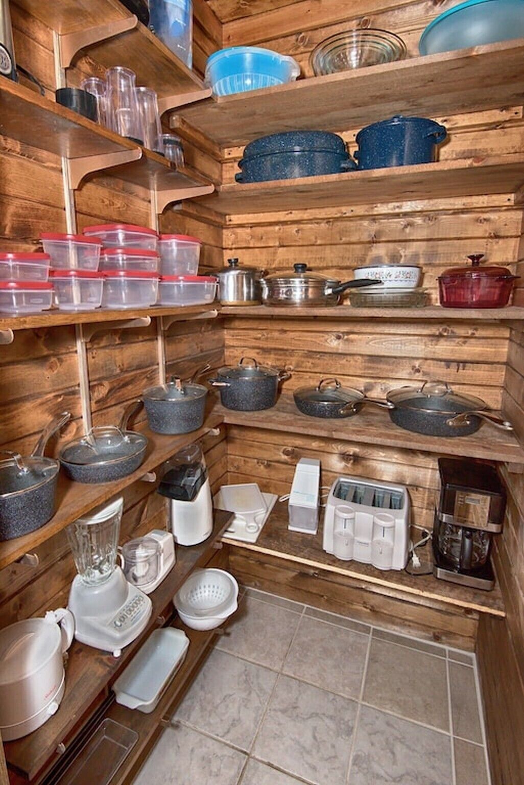 Une cuisine avec des étagères en bois où sont rangés divers ustensiles de cuisine, notamment des casseroles, des poêles et des boîtes de conservation.