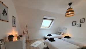 Un dormitorio moderno y luminoso con dos camas, un tragaluz y piso de madera.