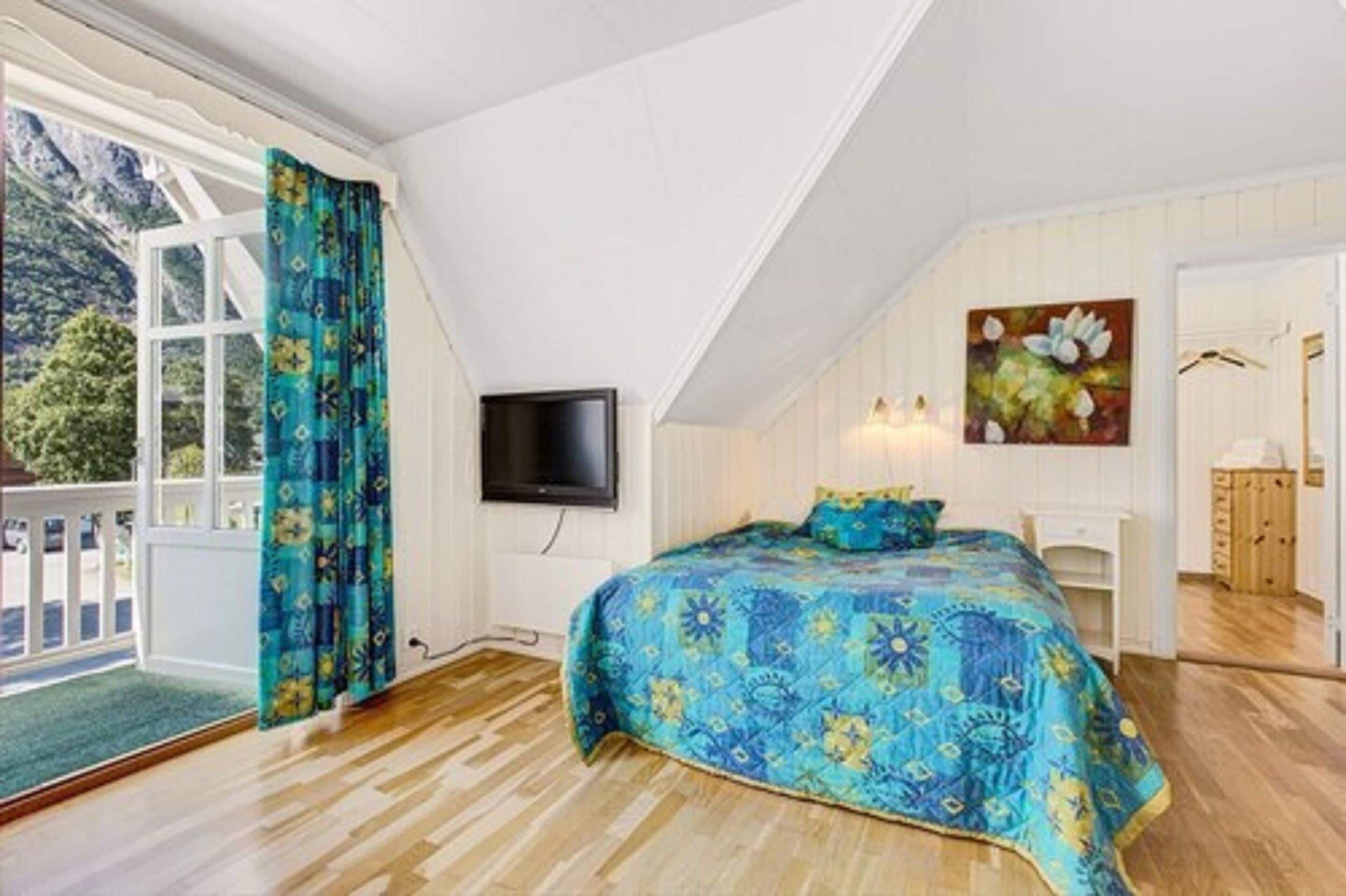 Una camera da letto con un letto grande, una televisione, un quadro e vista su un balcone.