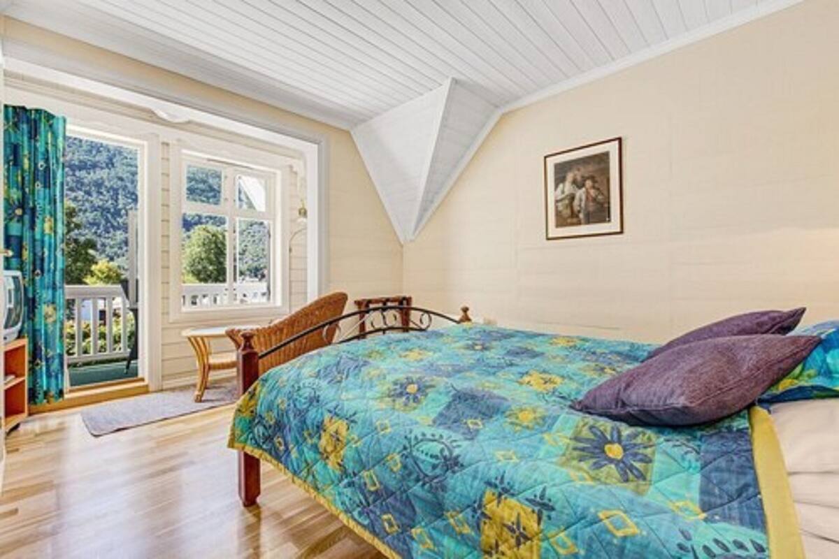 A bedroom with a bed, a chair, a window, and a picture on the wall.
