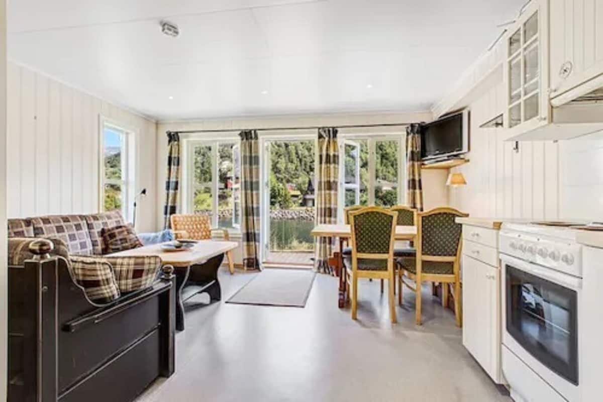 A compact kitchen with a dining area, a sofa, and a television.